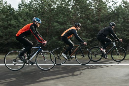 三名男子在风景秀丽的户外道路上一起骑自行车，展现了团队合作与运动能力