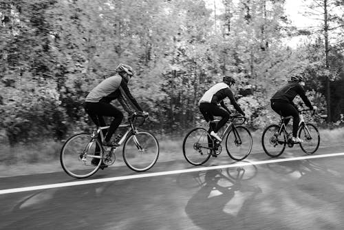 A Grayscale Photo of Men Riding Bicycles on the Road