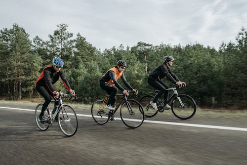Free Group of Men Riding Bicycle on Road Stock Photo