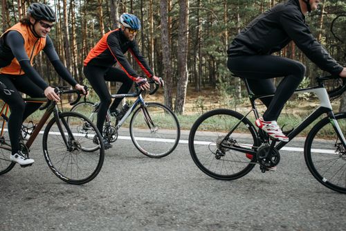 Free Men cycling on a forest road, enjoying outdoor leisure and fitness activity. Stock Photo