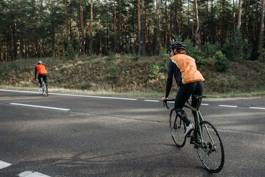 Two cyclists wearing reflective vests riding on a forest road, embracing nature and fitness.