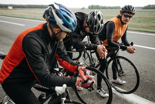 Three cyclists resting on a rural roadside, taking a break from their ride in sporty attire.
