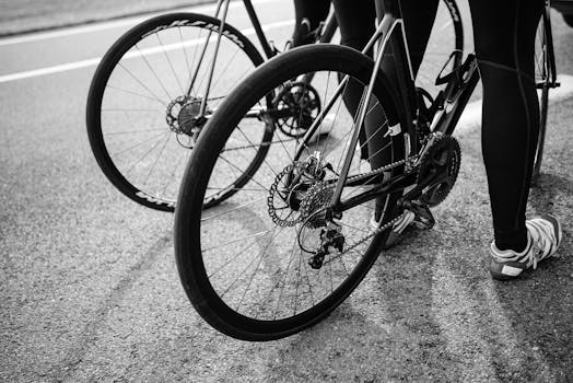 Black and white image of cyclists with road bikes on an asphalt road, showcasing wheels and gear.