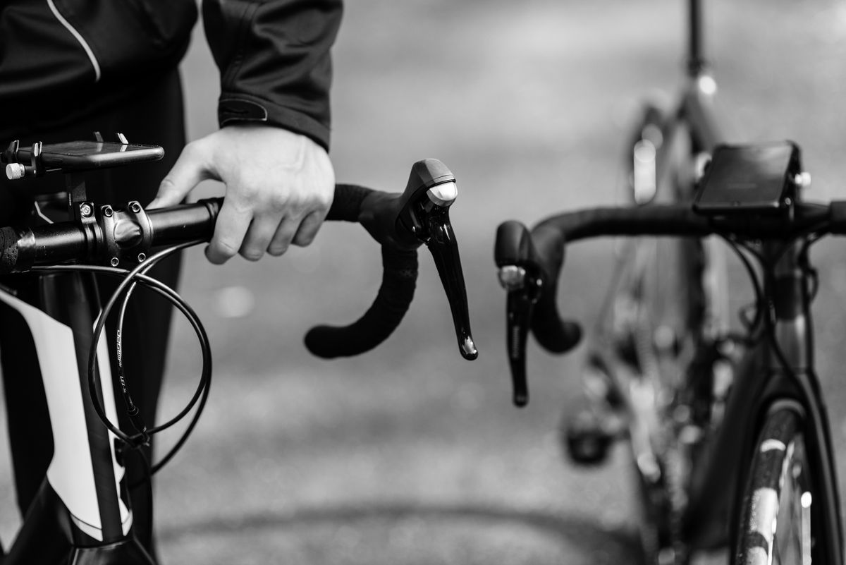 Handen op het onderstuur in winterjas — pasvorm en houding op de racefiets