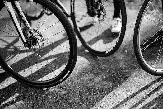 Black and white image of multiple bicycle wheels casting shadows on the ground.