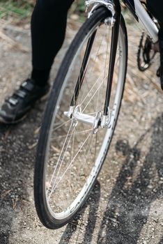 Detailed view of a bicycle wheel on a gravel path, emphasizing the spokes and road texture.