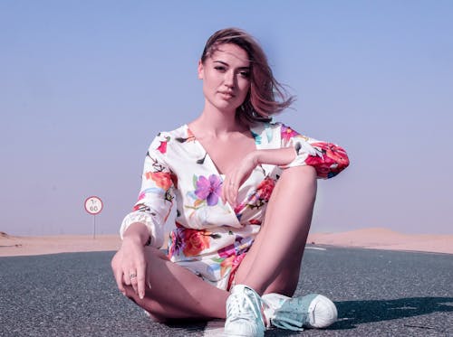 Woman in Floral Romper sitting on the Road