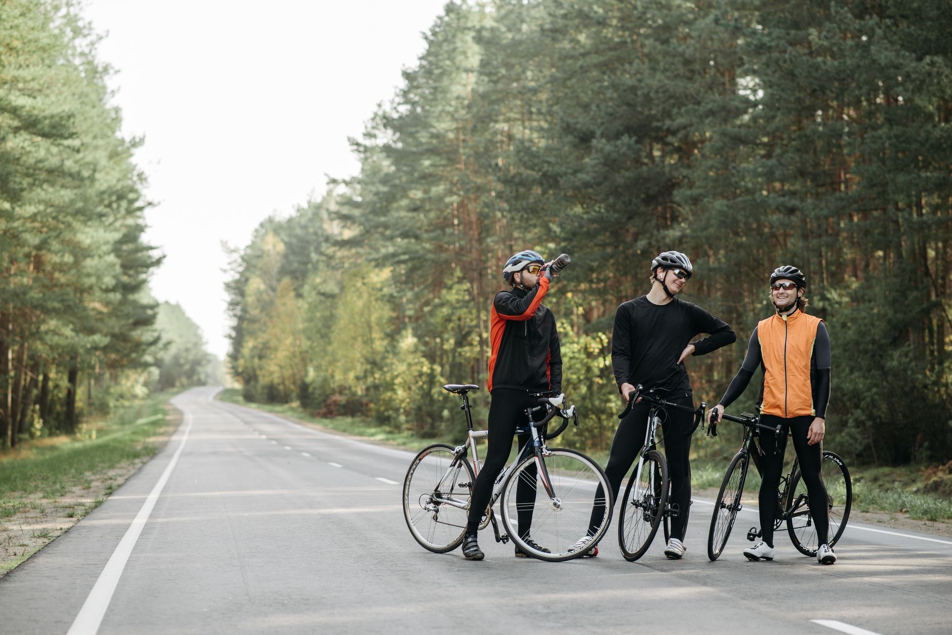 Three cyclists pause for a break in a serene forest setting, enjoying the outdoors.