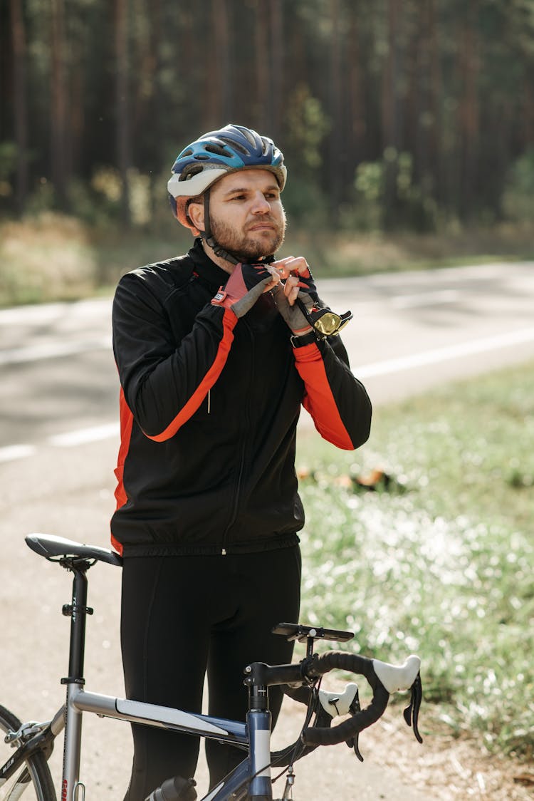 A Man Standing Beside His Bicycle While Wearing A Helmet