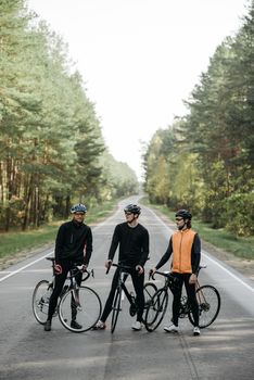 三个骑自行车的人站在森林道路上，完美展现了户外运动和冒险的形象