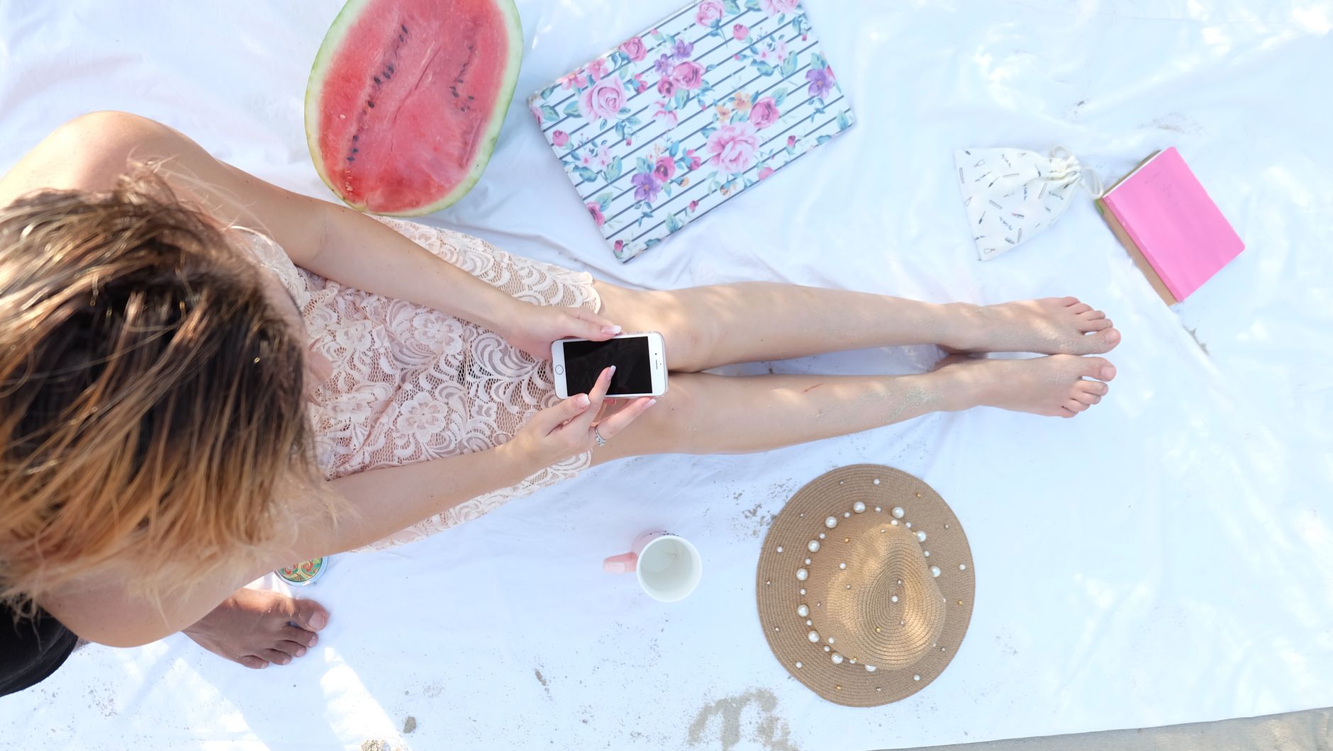 Woman enjoying summer beach day with smartphone and watermelon. Perfect relaxation.