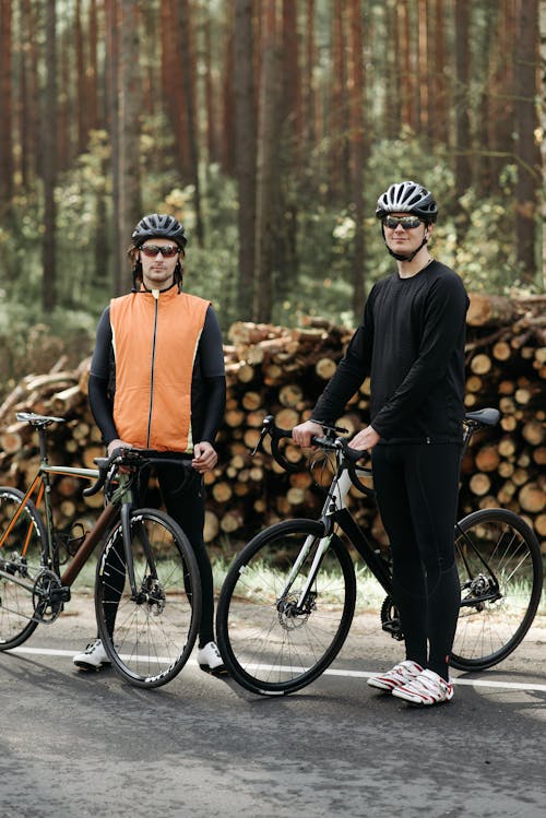 Cyclist Standing Beside Wood Logs