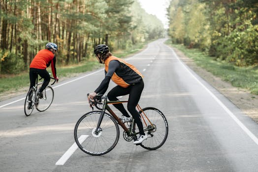 Two cyclists wearing helmets and sportswear biking on a forest road.
