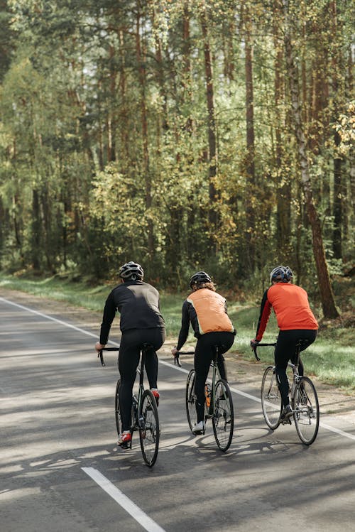Three Men Riding on Bicycles on Road
