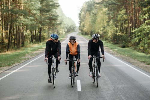 Three Men Riding on Bicycles on Road