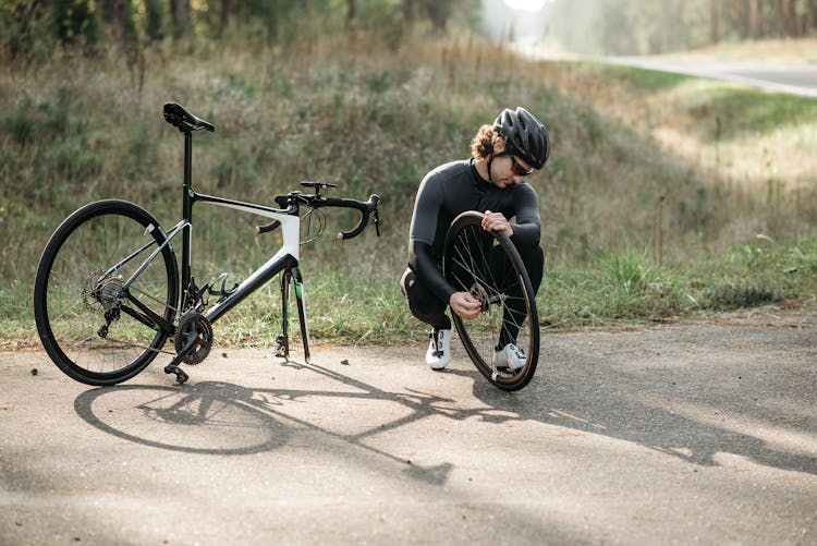 Man In Black Long Sleeve Shirt Fixing Bike Tire