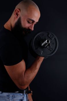 Side view of a man lifting a dumbbell in a low-key portrait style, showcasing strength.