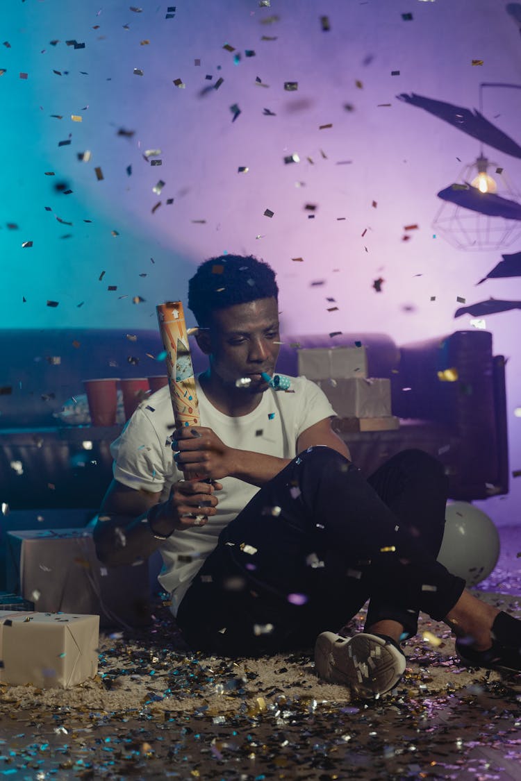 Man Holding Party Poppers While Sitting On The Floor 