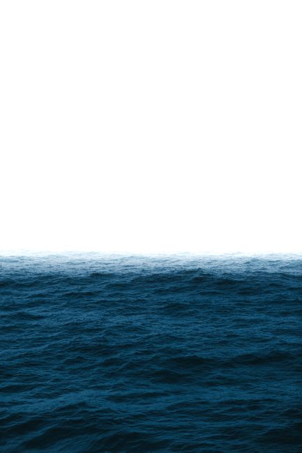 Picturesque scenery of deep blue sea with ripples and foamy waves meeting cloudless sky in sunlight