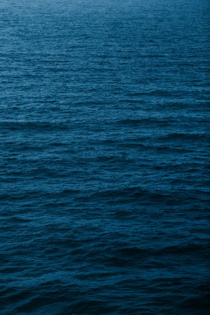 From above of endless blue waving ocean water with rippling surface in daytime