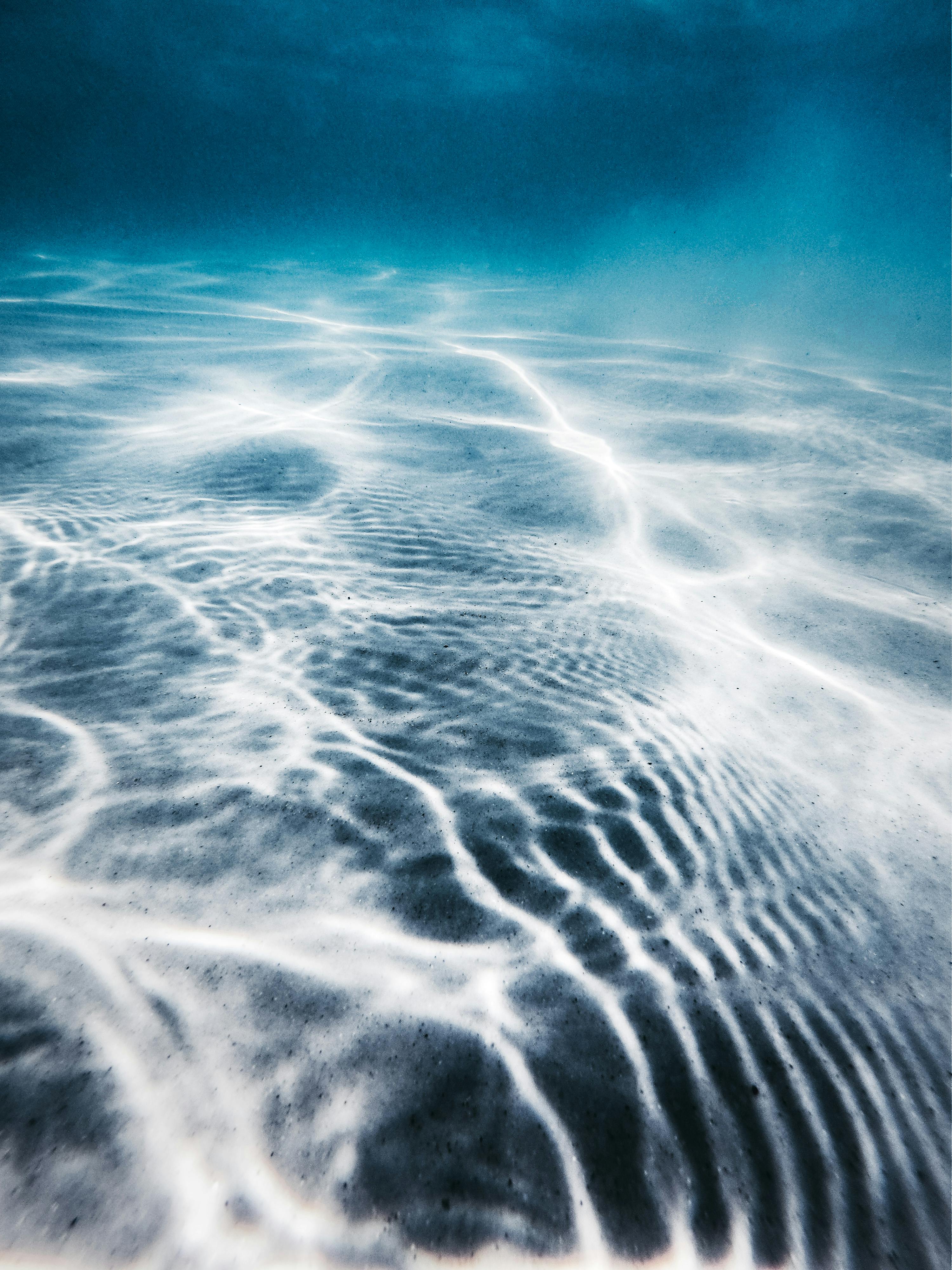 High angle of sandy bottom of blue ocean with clear water on sunny day
