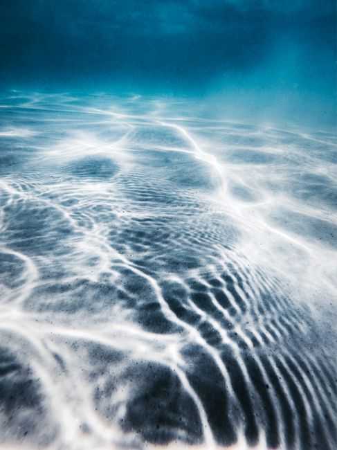 High angle of sandy bottom of blue ocean with clear water on sunny day