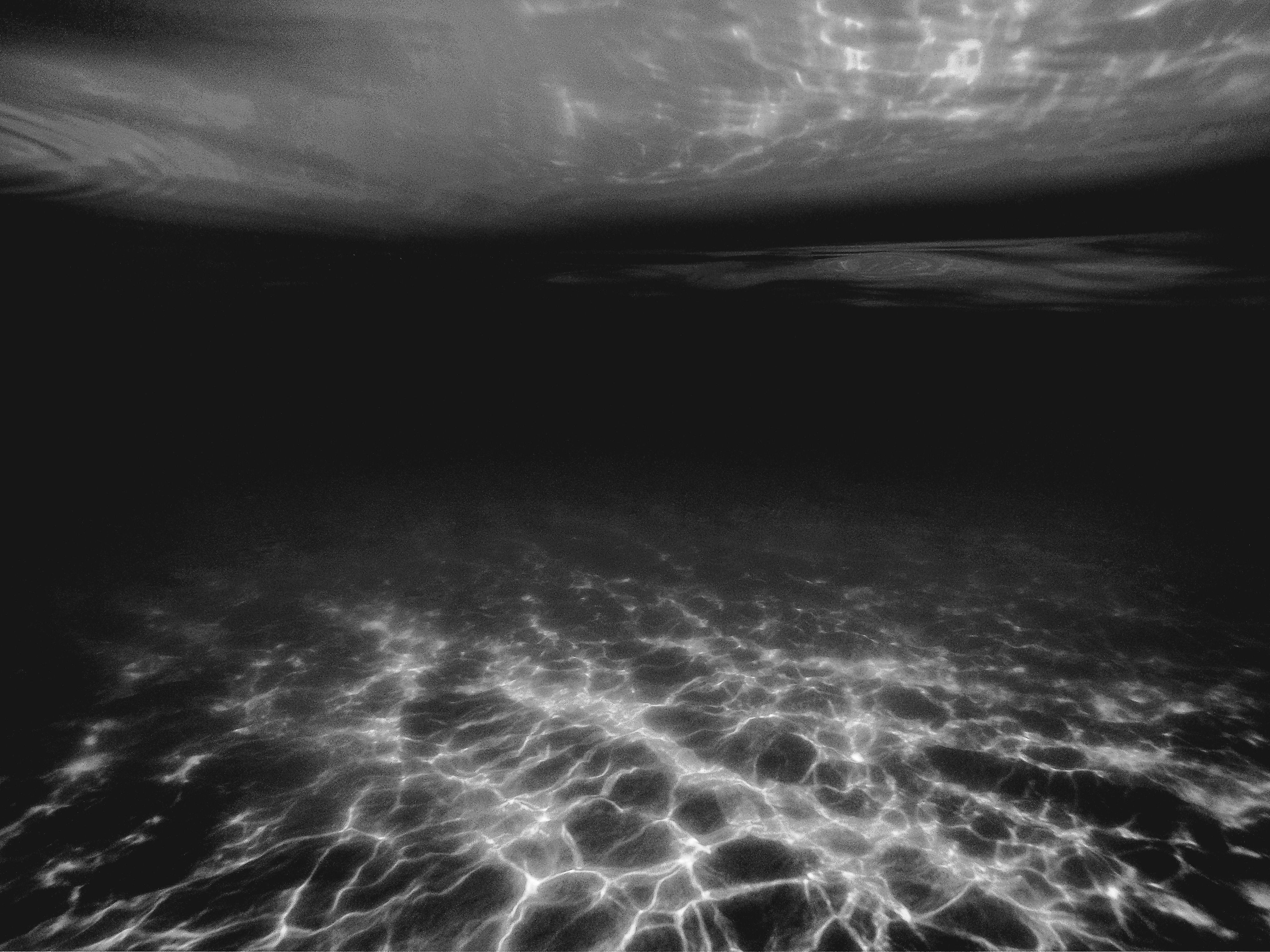A serene underwater scene with light reflections in monochrome tones, evoking tranquility.
