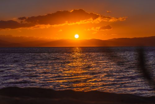 Free Golden ocean sunset with clouds casting a vibrant glow over the calm sea. Stock Photo