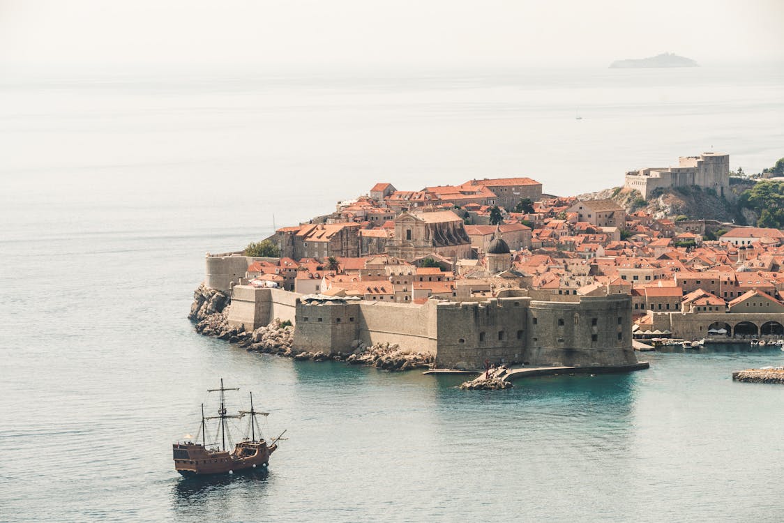 Free Brown Sailing Ship Near Building Stock Photo