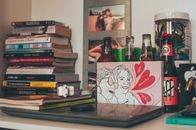 Shelf with stacked books laptop and drink bottles