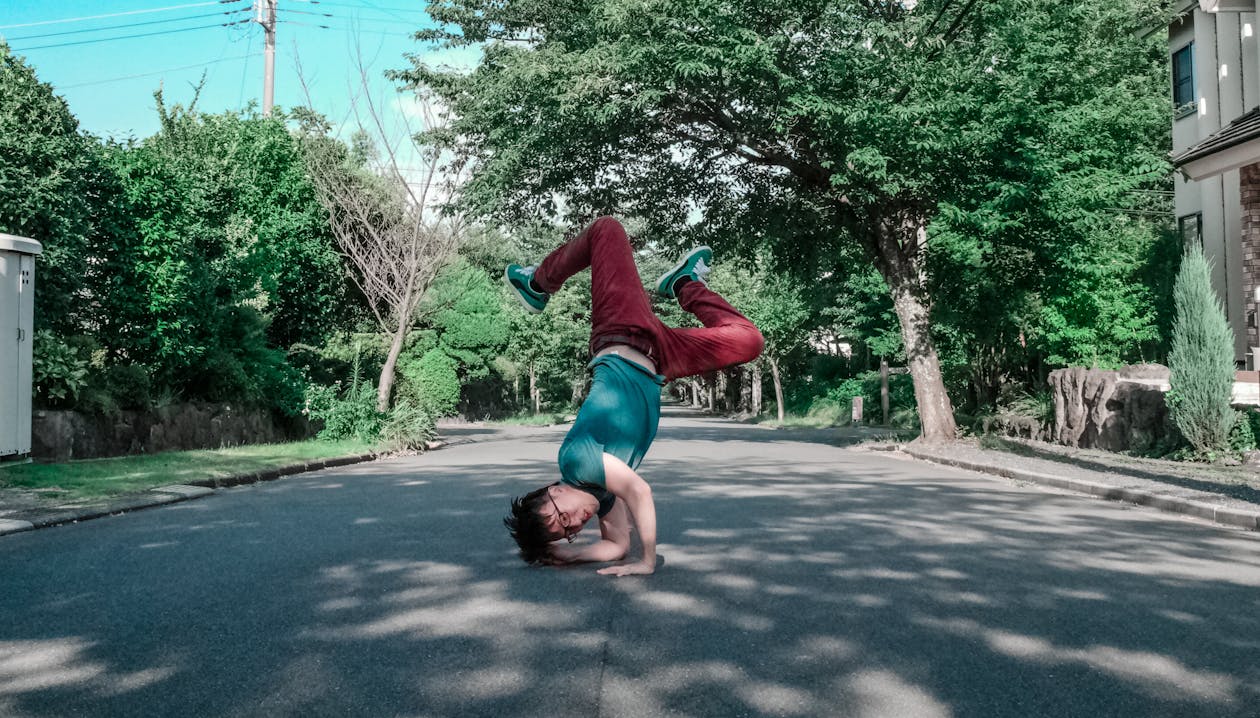 Free Man Doing Head Stand on Road Stock Photo