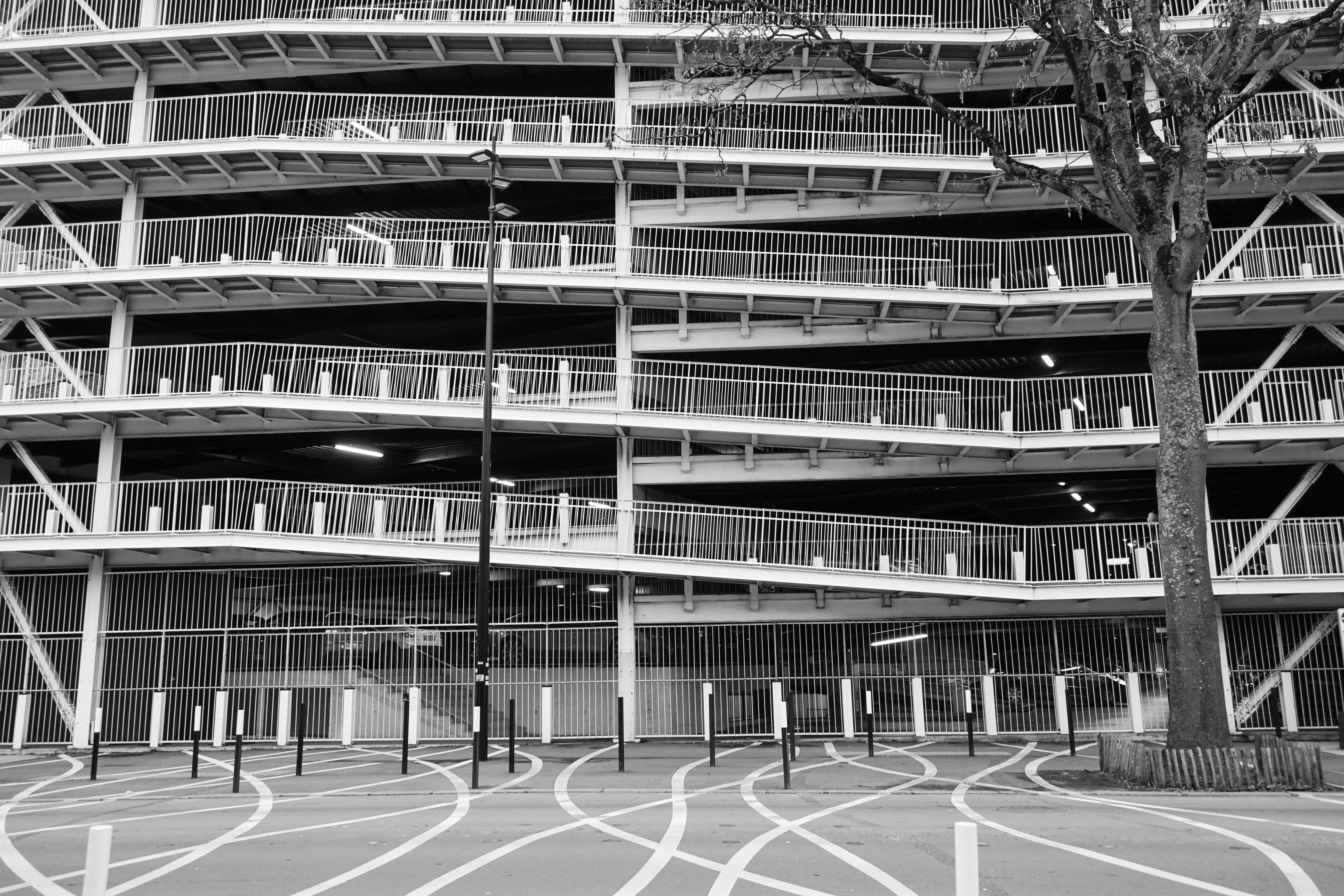 Grayscale photo of a spiraling multi-story parking structure with modern design.