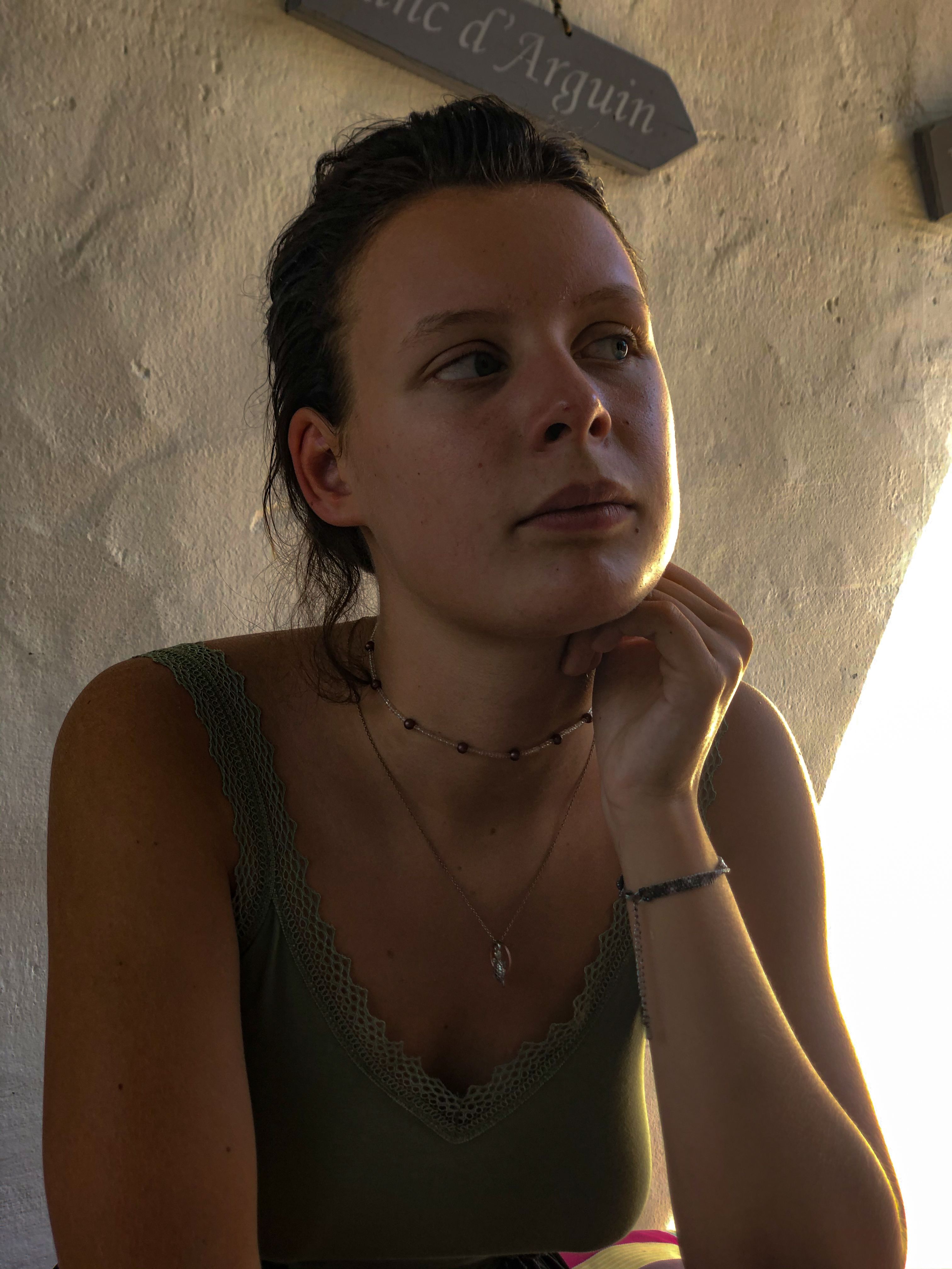 Portrait of a woman in Arcachon, France wearing a green top, captured indoors with a thoughtful expression.