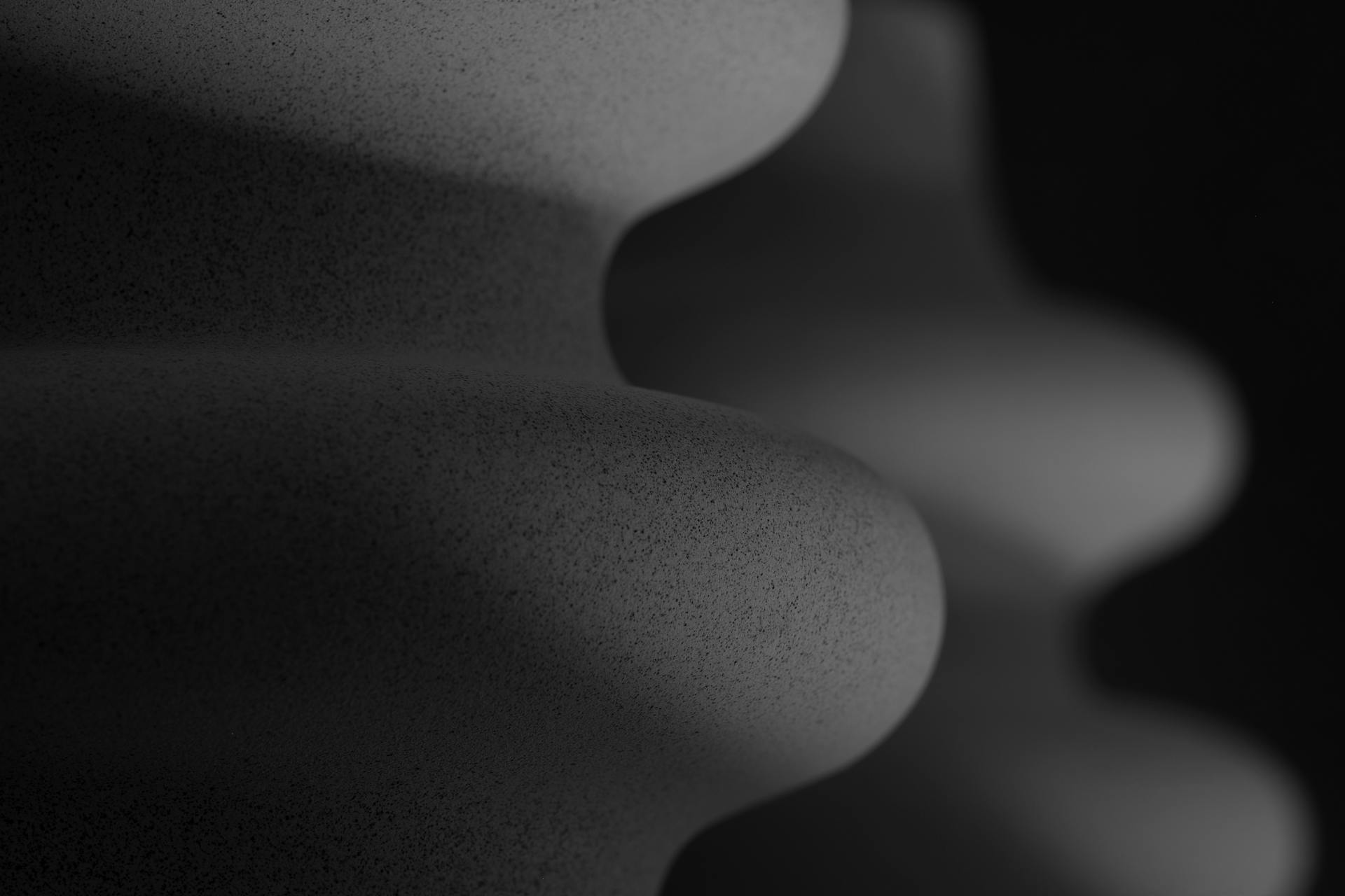 Close-up of a speckled, corrugated object with curved patterns in grayscale.