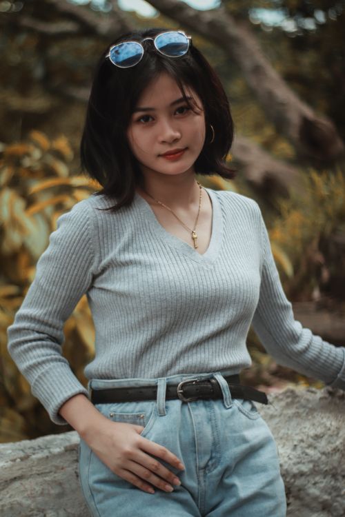 Free Portrait of a stylish young woman outdoors, wearing a sweater and sunglasses. Stock Photo