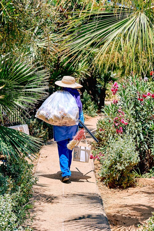 A Person Walking in a Pathway  Carrying a Plastic Bag