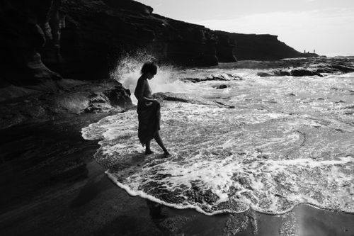 Free A serene black and white photo of a woman on a rocky beach in Hawaii, USA. Stock Photo