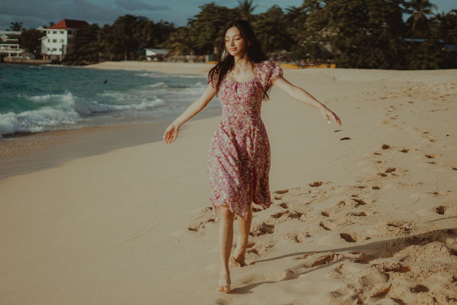 A woman in a floral dress walking on the beach