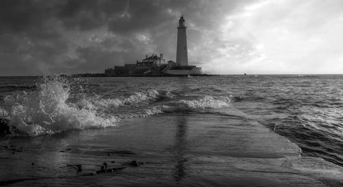Grayscale Photo of a Lighthouse Surrounded by the Sea