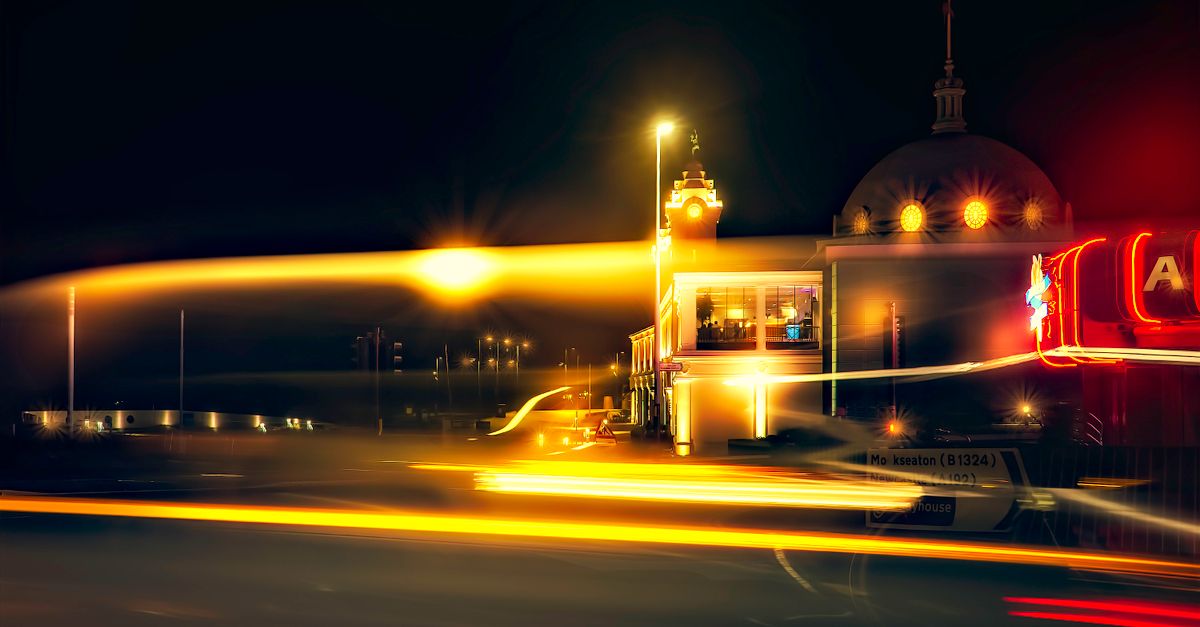 Long exposure photo of light trails near an illuminated dome at night.
