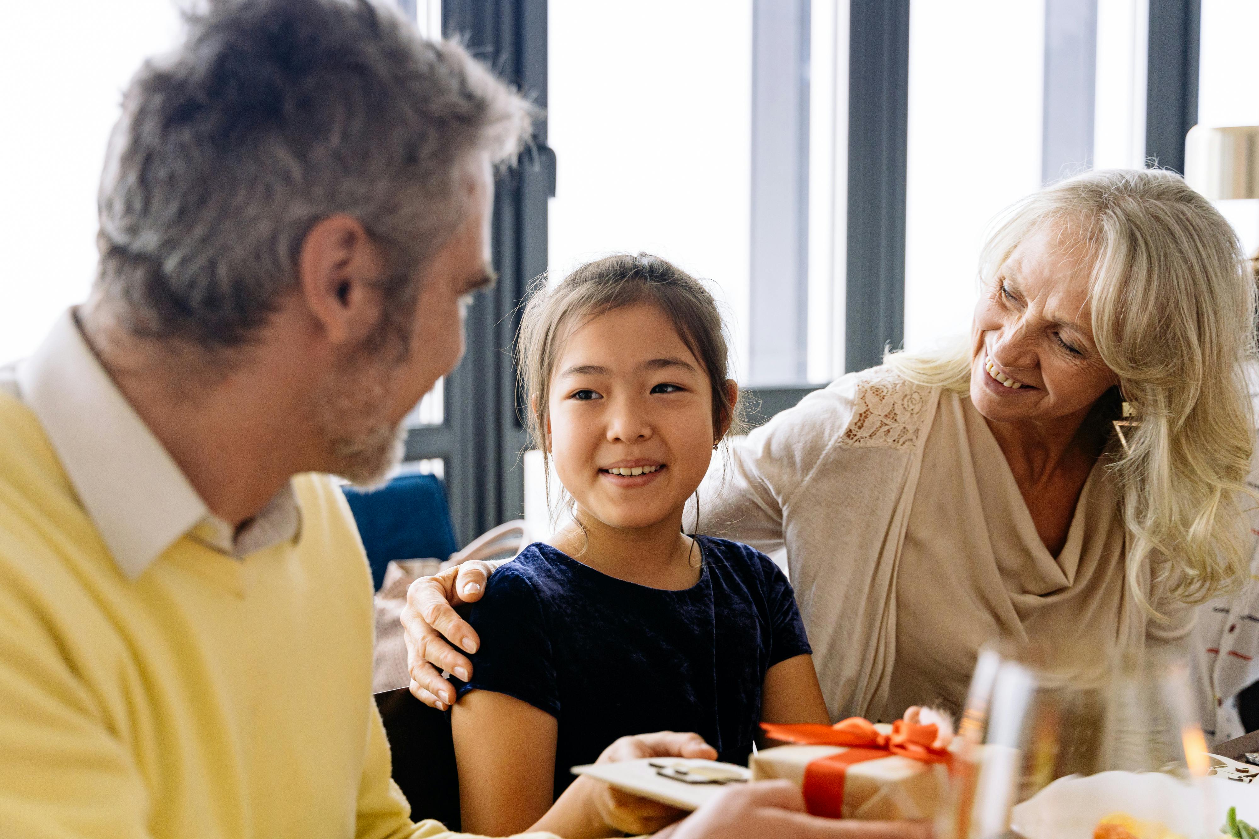 a girl sitting between elderly couple