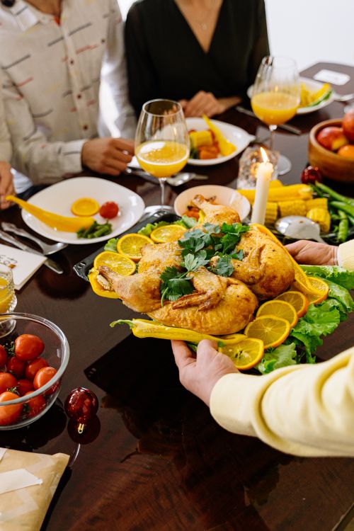 Free A delicious roasted chicken with lemon slices being served at a festive family dinner table. Stock Photo