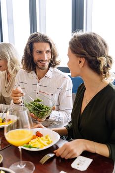 一群成年人在室内享用早午餐，分享食物与微笑，气氛充满活力与活泼