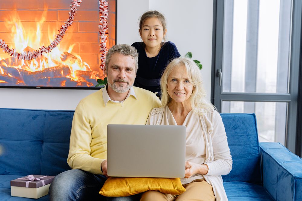 A grandmother, her daughter and grandchild smiling around a laptop