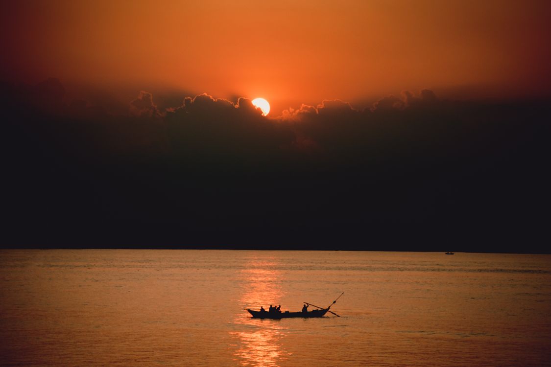 Silhouette of Boat on Body of Water During Sunset · Free Stock Photo