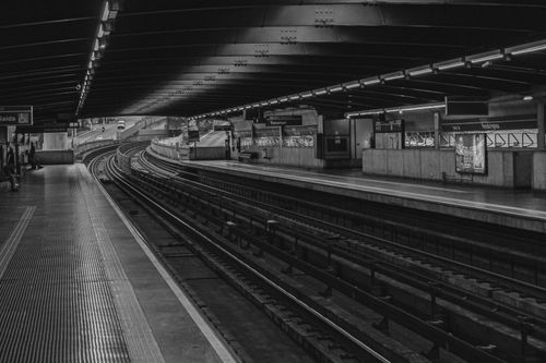 Free Moody black and white image of an empty subway platform with curving tracks. Stock Photo