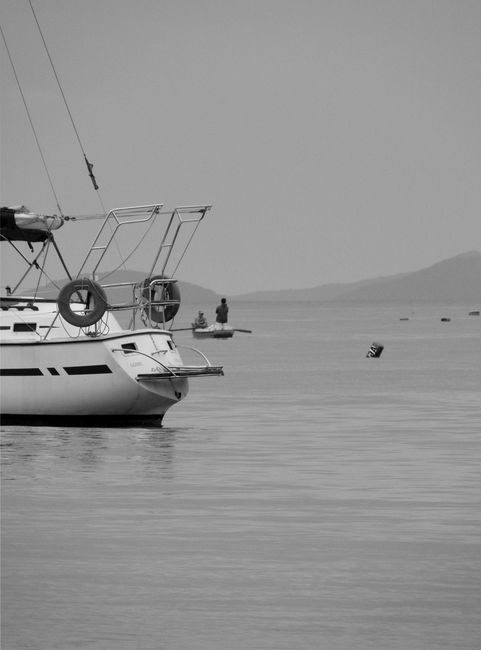 Black and white photo of a yacht on calm ocean water, conveying tranquility.