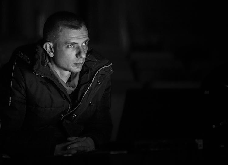 Serious Young Man Looking At Screen Of Laptop At Night