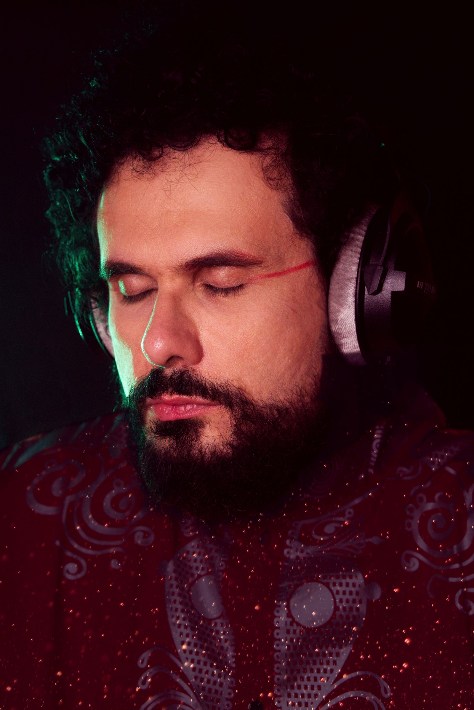 Portrait of a man with closed eyes wearing headphones against a dark background