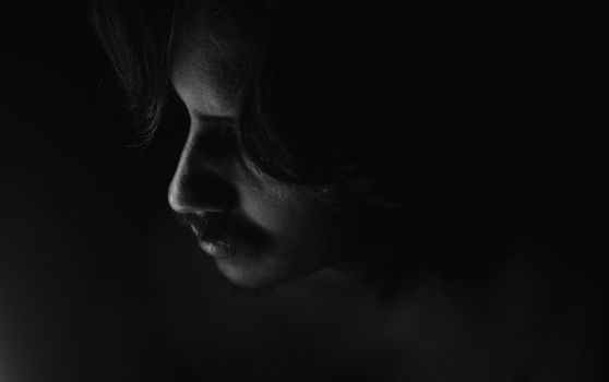 Artistic black and white photo capturing a mysterious man's profile in low light.
